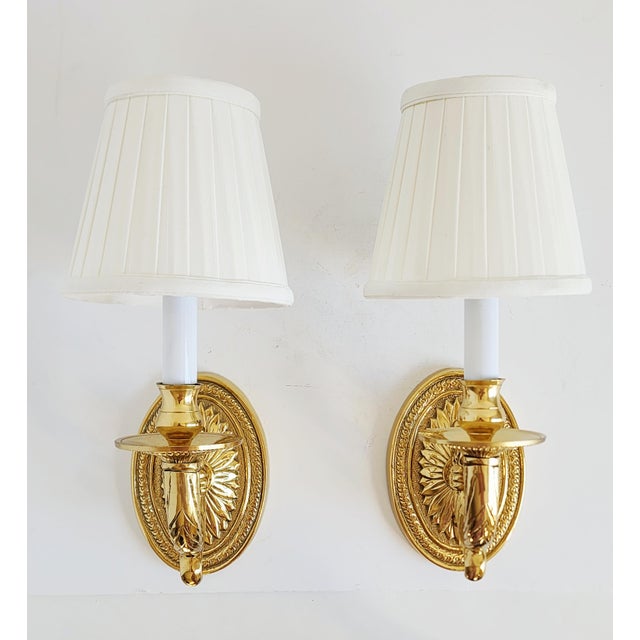 Pair of solid brass Neoclassical style wall sconces with ornate scroll arm, beaded bobeshes and acanthus leaf motif back...