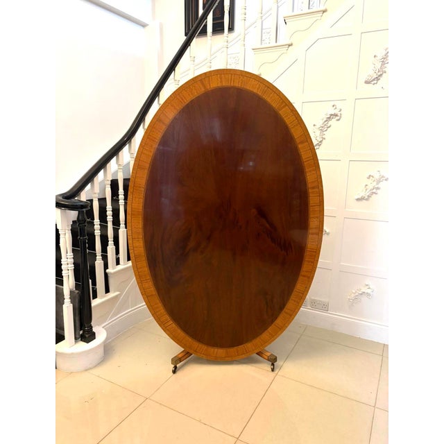 An antique Regency style figured mahogany oval dining table of outstanding quality, featuring a beautifully selected and...