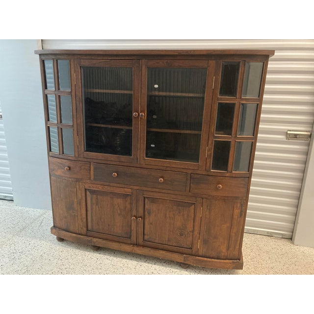 A finely crafted solid wood butler’s pantry or haberdashery with tinted and beveled glass doors on top, three middle...