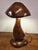 This sculptural table lamp is hand-carved from a single solid piece of hardwood, likely walnut or acacia, and shaped into...