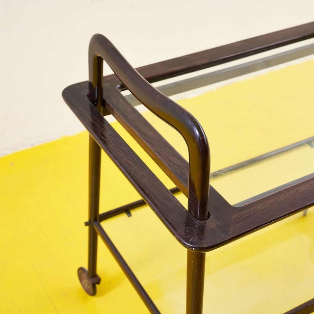 Discover the timeless appeal of this refined glass serving cart. Featuring a burnished metal frame and clear glass...