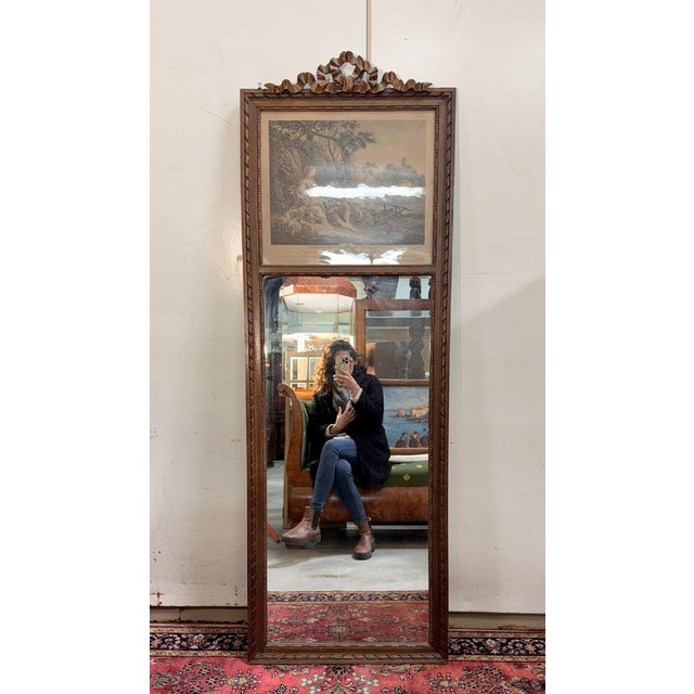Louis XVI style carved wood trumeau mirror topped with a ribboned bow decorated with a gallant scene in the spirit of the...