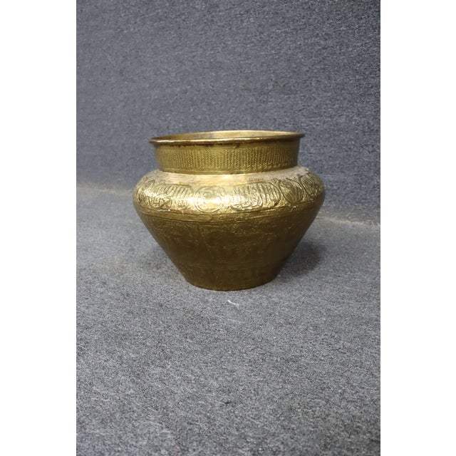 Brass pot with detailed engraved decoration throughout, featuring geometric and figural motifs. Rounded form with a wide...
