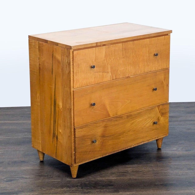 This sturdy dresser features a clean, mid-century modern design with three spacious drawers and simple, round metal knobs....