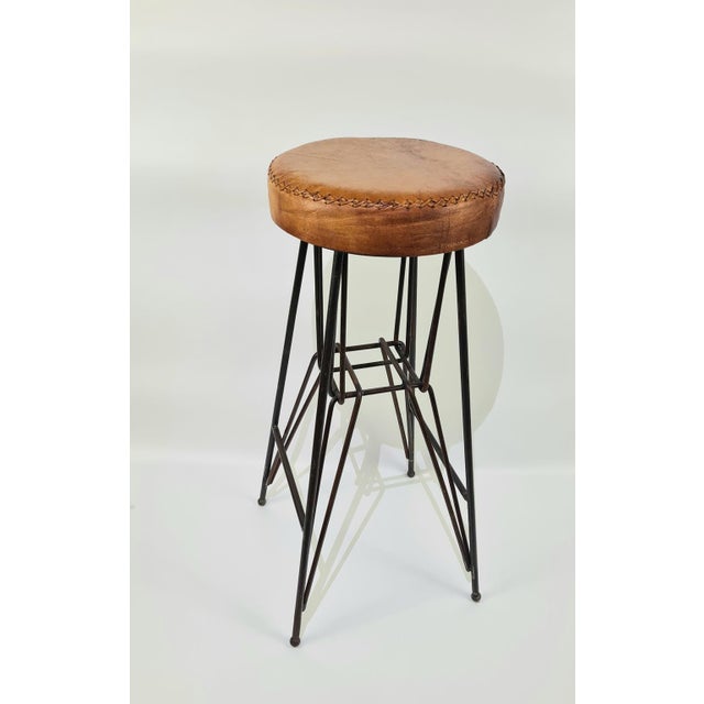 An original industrial stool/bar stool from the mid-20th century, made of steel and a thick, natural leather seat with...