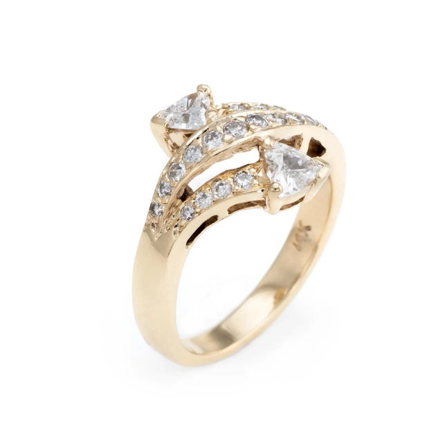 Finely detailed vintage diamond bypass ring, crafted in 14 karat yellow gold. Two heart shaped diamonds are estimated at...