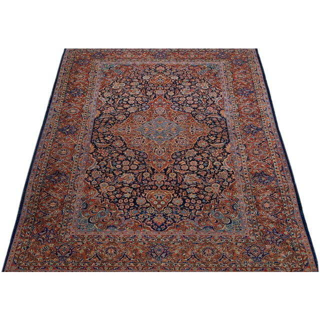 Beautiful Antique Kashan hand-knotted wool rug with a navy blue field. This Persian rug has red, pink, and beige accents...