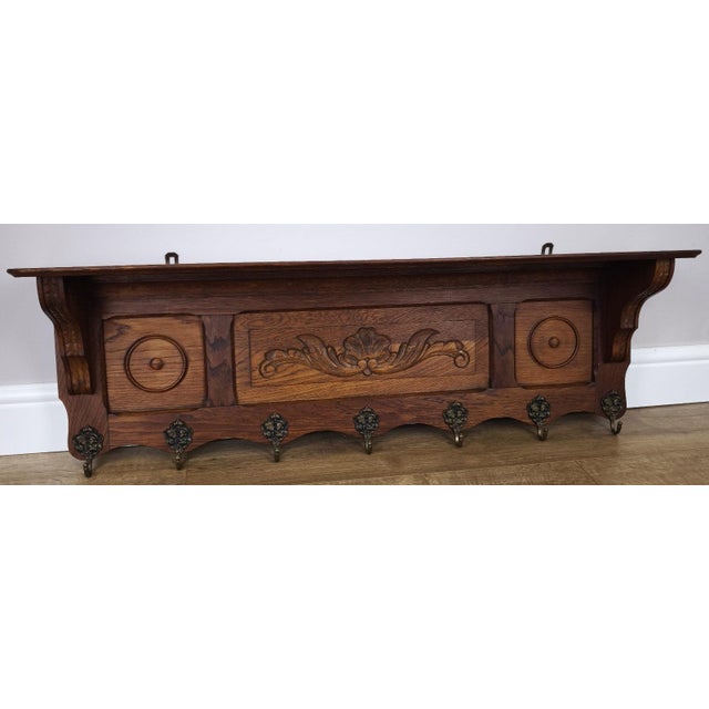 A striking Vintage French coat hanger, beautifully designed with rich oak tones, intricate carved detailing, and an...