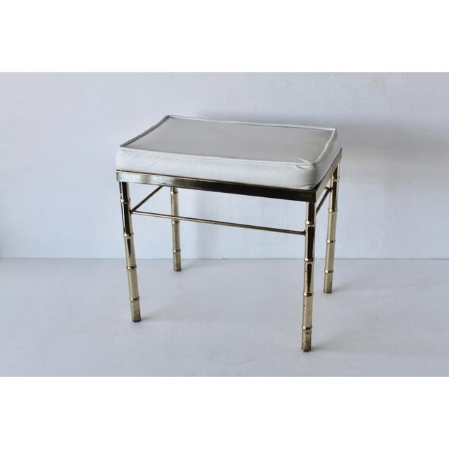 Hollywood Regency vanity bench featuring a faux bamboo brass/gold finish frame and a white vinyl cushion in a George Koch...
