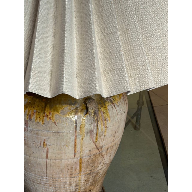 A monumental custom table lamp. The base is a 19th century Spanish terra-cotta olive jar, featuring a drip glaze in shades...