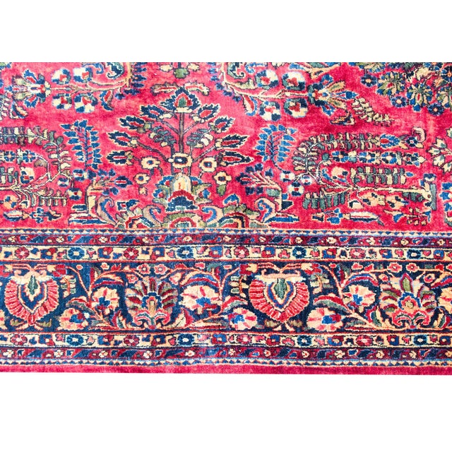 A traditional early 20th century Persian Sarouk rug with a mirrored floral pattern with myriad floral clusters, surrounded...