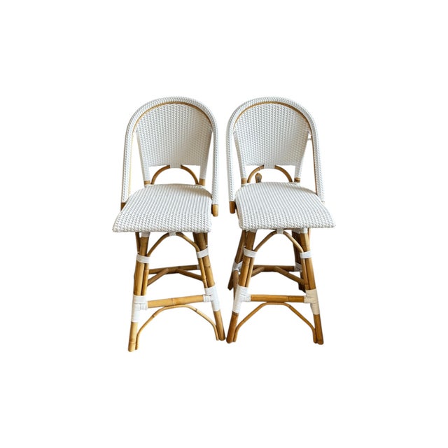 A beautiful pair of Serena & Lily swivel bar chairs featuring a classic coastal design with natural rattan frames and...