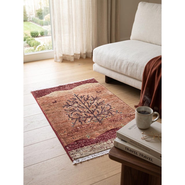A hand-knotted Afghan Gabbeh rug in the Persian Gabbeh tradition, woven on a warm terracotta ground with a single tree of...