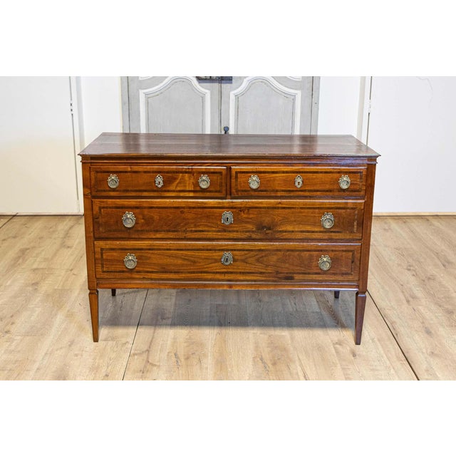 An Italian Neoclassical period walnut and mahogany four-drawer commode from circa 1790 with cross banding, classical...