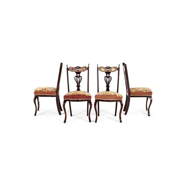 A set of four victorian mahogany dining chairs with fine embroidery work floral seat cushions and back rests. The chairs...