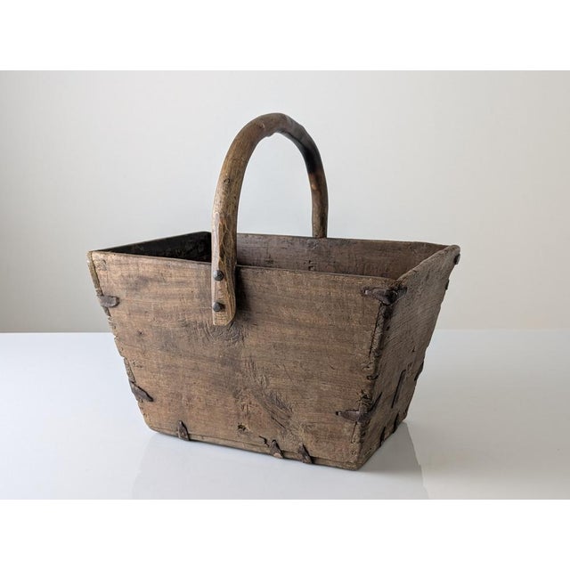 Rustic wooden container constructed from solid wood planks and reinforced with staples and hand-forged iron fittings. The...