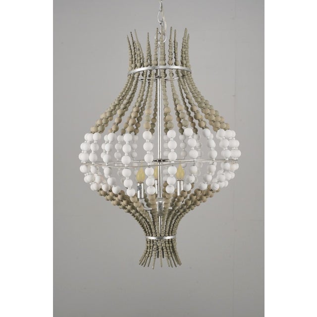 Bohemian style pendant light made of tan and white wood beads, brushed steel supports, and a chain fitter. This light...