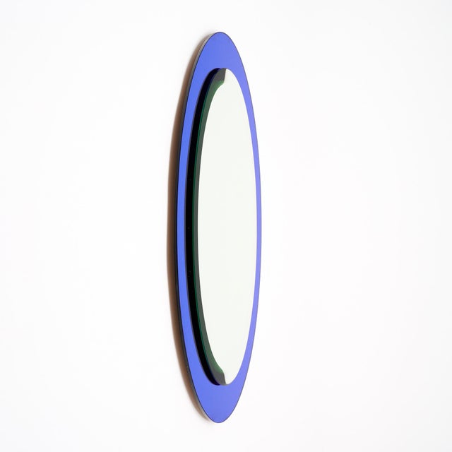 Vintage mirror from Italy featuring a central oval mirror with bevel and a cobalt blue glass frame supporting it. This...