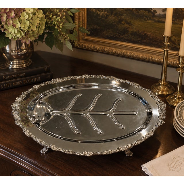 An elegant vintage silverplate carving platter featuring a traditional raised tree-and-well design, an ornate floral and...