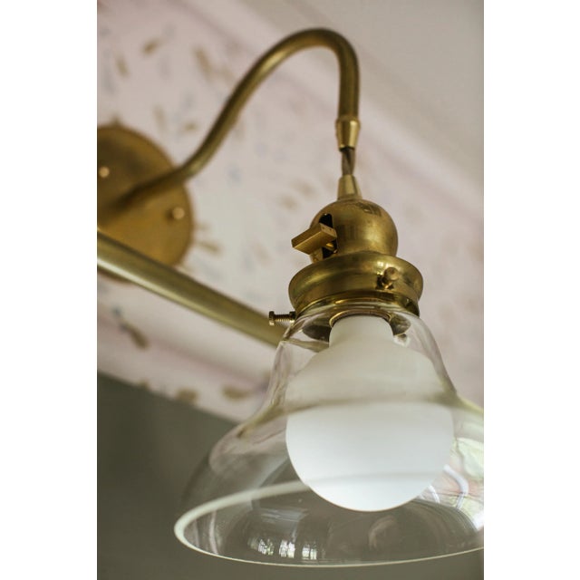 The unique design of this sconce stands out in any home: A matte white bulb housed under a clear, bell-shape shade,...