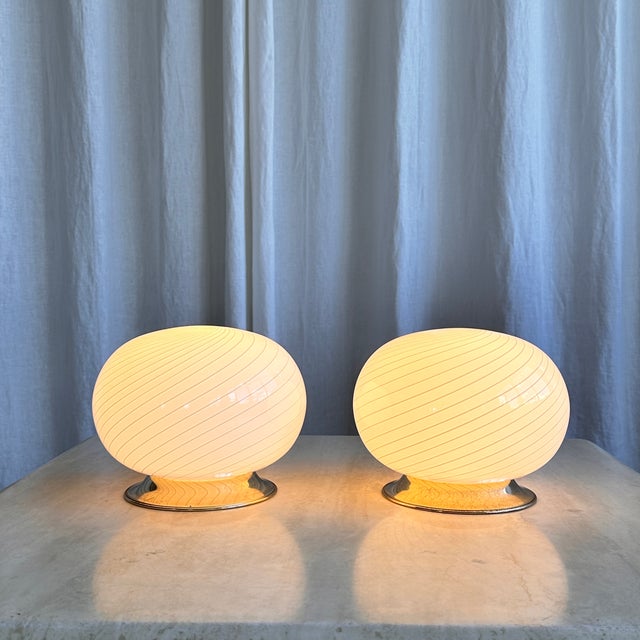 White swirl Murano glass table lamp with brass base. The legendary swirl pattern acquires a warm, light yellow or beige...