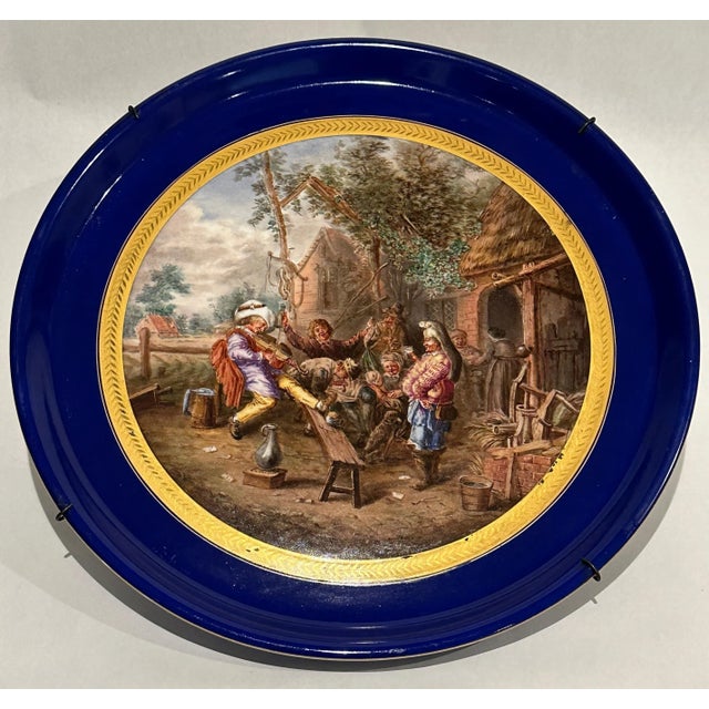 This large French porcelain charger, in the Sèvres style, is intricately painted with a period courtyard scene, set in the...