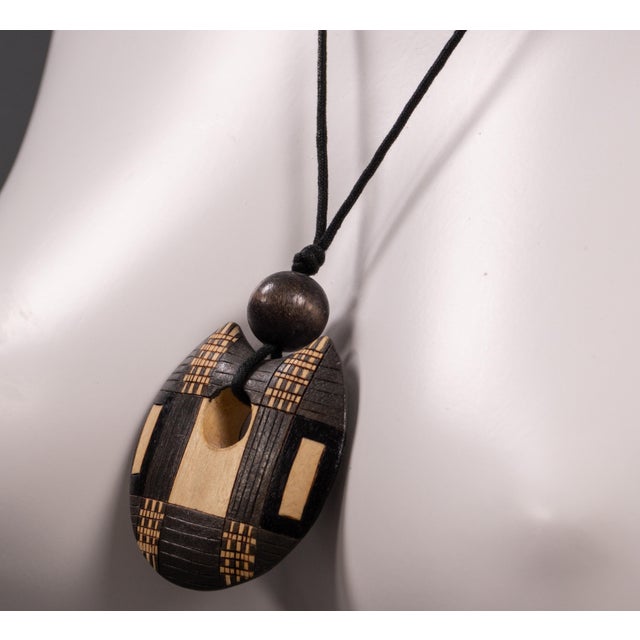 This drop shaped wooden pendant dates back to the 1980s and features an interplay of organic and geometric shapes. The...