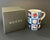 "Guccissimo" porcelain mug featuring bright polychrome design with a predominance of blue and large letters forming the...