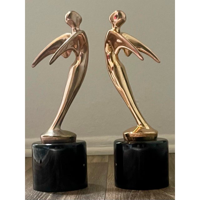 Vintage Hollywood Regency style winged abstract figural Telly award statues, gold tone plated metal with round black...
