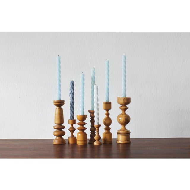 A decorative set of seven wooden candleholders of varying heights and individually designed, turned shapes. Each has its...