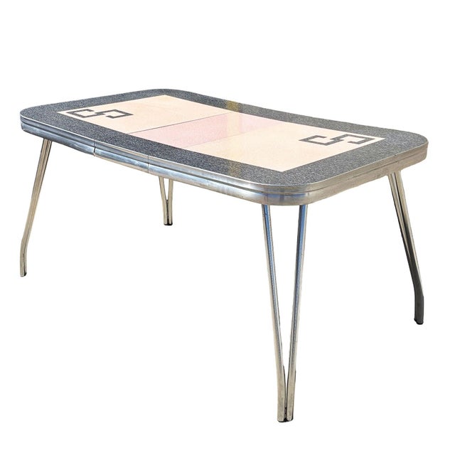 A striking Mid-Century Modern chrome and pink Formica dining table featuring a sleek atomic-age design. The tabletop...