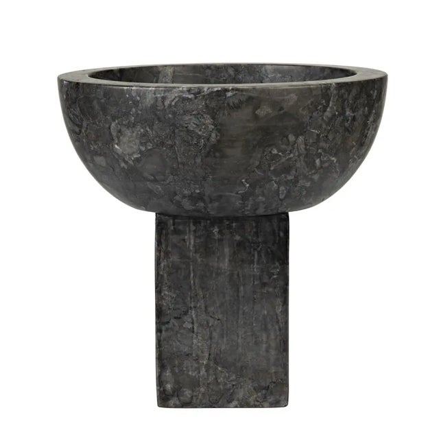 The simple geometry of a sliced sphere, and an elongated cube combine in this chunky pedestal bowl. A catch-all, a vase, a...