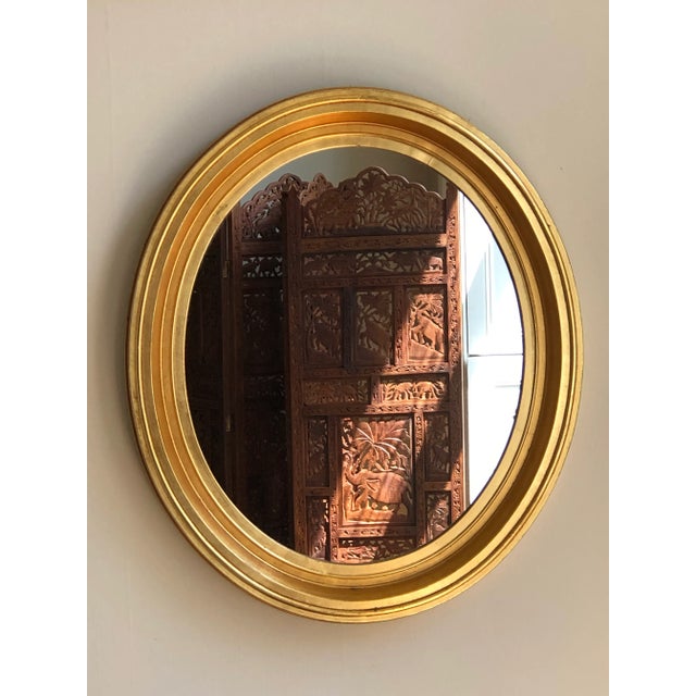 Offering a gorgeous mid-20th century giltwood oval wall mirror in the French Louis Philippe style. The bright gold gilt...