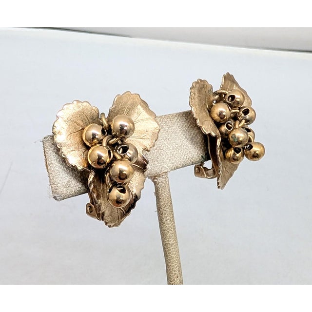 1950s goldtone textured leaf with goldtone ball beads grape cluster clip earrings. Marked "NAPIER PAT. PEND." on the...
