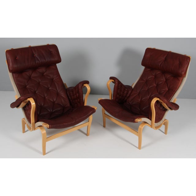 Bruno Mathsson Pernilla lounge chair with patinated red leather. Frame in beech. Made by DUX. This piece is attributed to...