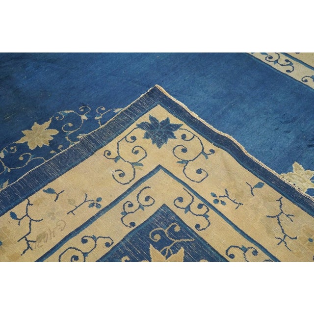 From northeast China, this export carpet shows a deep blue field organized by an open arabesque and four paeony medallion,...