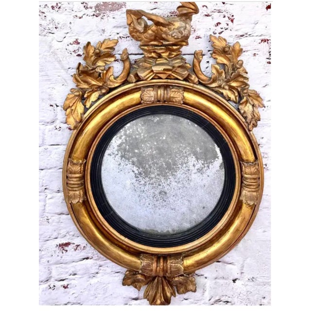 Early 19th century circular regency giltwood convex mirror. Mirror features a carved dragon perched atop a structure of...