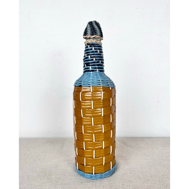 Vintage European wire wrapped bottle. Glass bottle wrapped on plastic wire. Attractive blue, black, and brown design.
