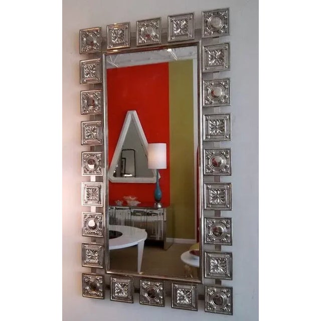 This unusual mid century modern 1950's mirror features alternate squares of two different impressed designs. A fleur de...