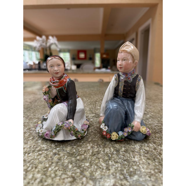 A pair of perfect Royal Copenhagen figurines of a boy and a girl dressed in traditional Danish dress by Carl Martin-Hansen