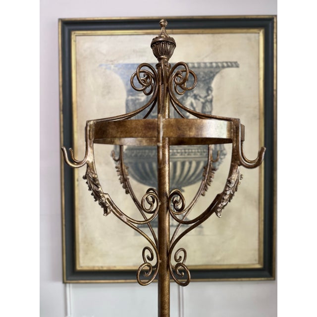 Elegant vintage metal hall stand with a warm gilt-toned finish, decorative scrollwork, and a beautifully ornate...