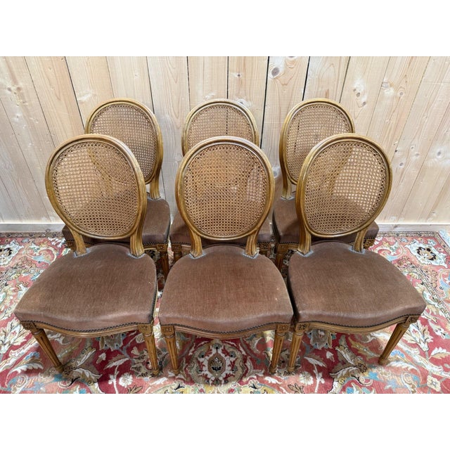 An elegant set of six Louis XVI style chairs, characterized by a caned medallion back and a generously padded, spring-...