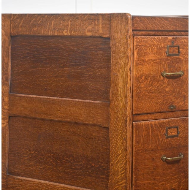 Early 20th-century oak filing cabinet featuring four stacked drawers, crafted in solid quarter-sawn oak with a rich, warm...