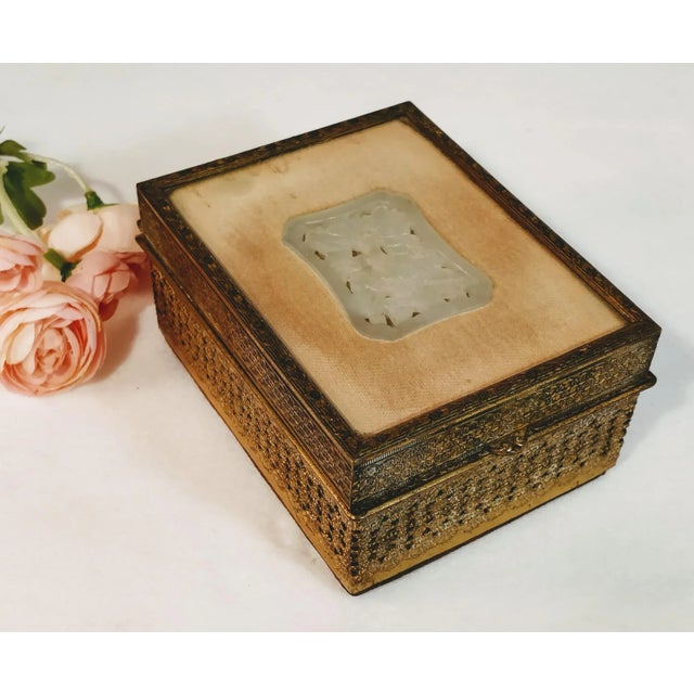 Stunning Chinese filigree gold gilt metal jewelry box with velvet lining and white carved jade insert. The jade is nestled...