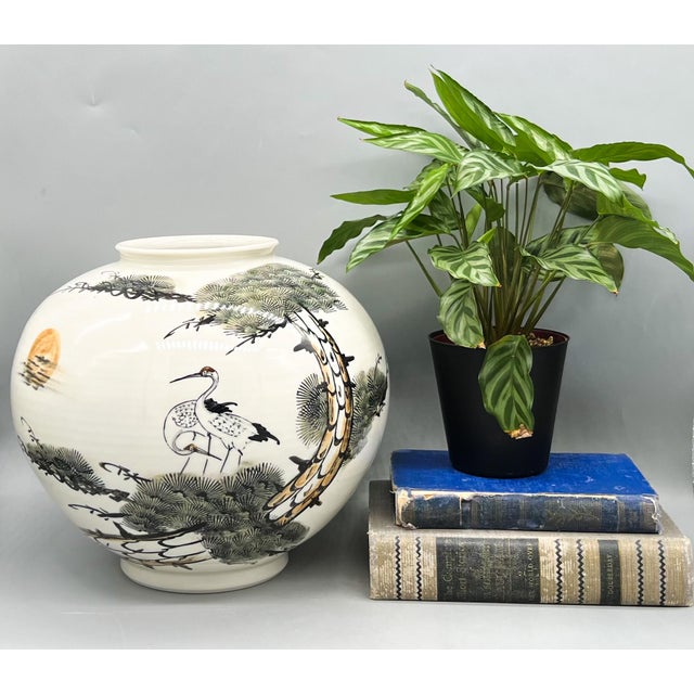 Captivating and large rounded porcelain vase with a crane and pine landscape in black, soft green, and warm sepia tones....