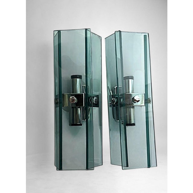 Elegant and linear pair of vintage Italian wall sconces. Each piece features a solid chrome-plated metal frame supporting...
