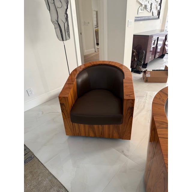 A pair of sculptural barrel-back lounge chairs featuring thick, curved wood frames with a striking, highly figured grain...