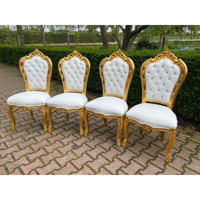 A striking 1970s Italian Baroque / Rococo Revival dining set, featuring a richly carved gilt dining table with a black...