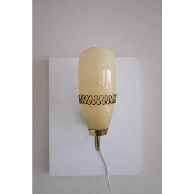 Beautiful Mid-Century Glass and Brass Wall light by Mauri Almari for Idman, Finland. Brass lamp arm with a filigree design...