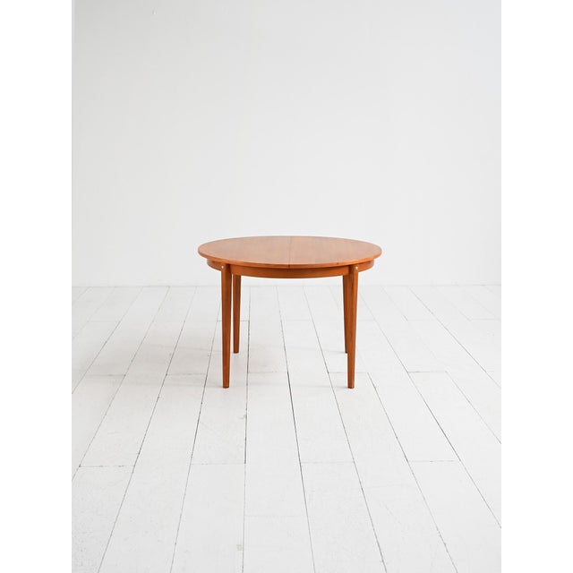 Extendable round teak veneer table with tapered legs. Scandinavian production, 1960s. Extendable round dining table,...
